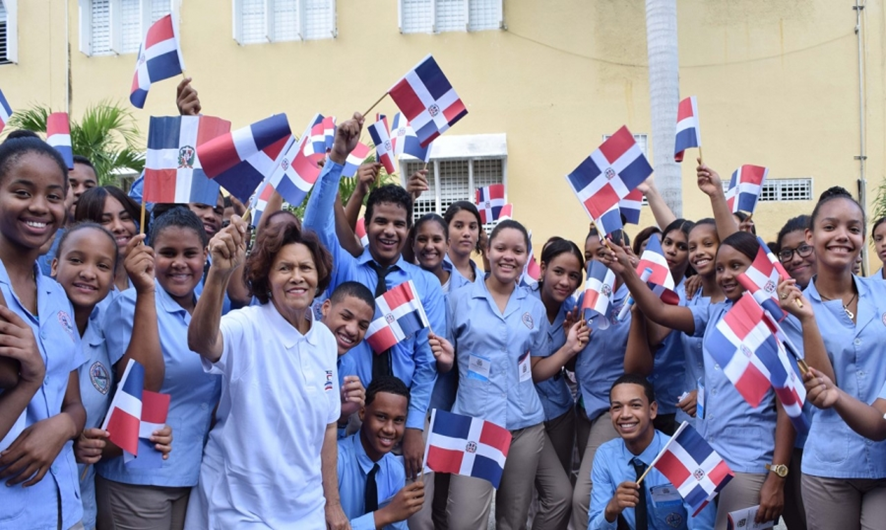 Jóvenes escolares portando la bandera tricolor de la República Dominicana.
